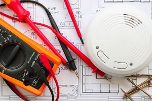 smoke detector on house plan with multimeter